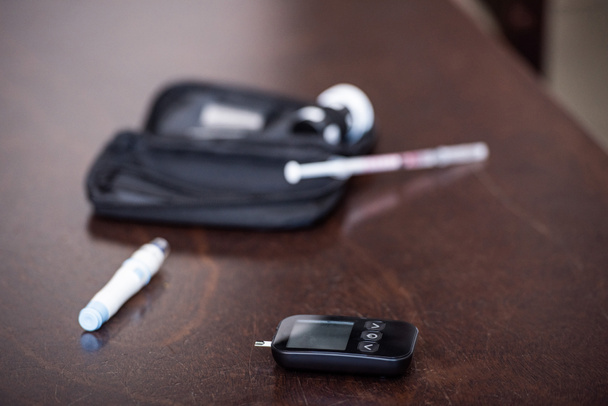 selective focus of glucose monitor near blood lancer on wooden table  - Photo, Image