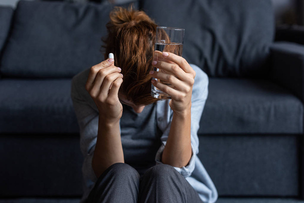 sick woman holding pill and glass of water at home - Foto, immagini