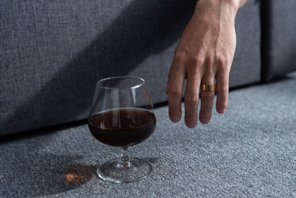 Teilansicht des Menschen mit Ring und Glas Cognac - Foto, Bild