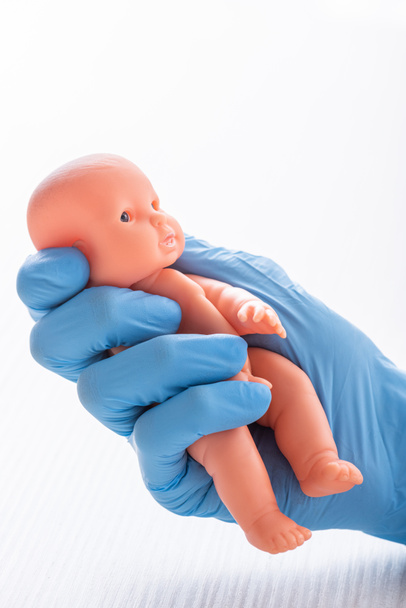 cropped view of doctor in glove holding baby doll - Photo, Image