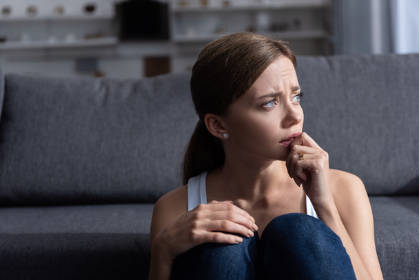 upset young woman with ring sitting near sofa in living room at home - Photo, Image