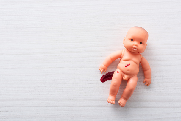 top view of injured baby doll with blood on table  - Photo, Image