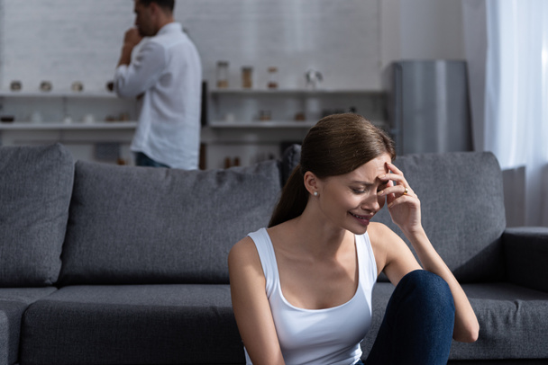 crying young woman on sofa and man in white shirt - Foto, afbeelding
