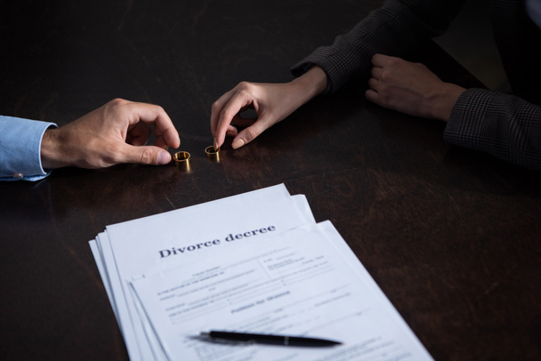 частичный взгляд пары за столом с документами о разводе и кольцами
 - Фото, изображение