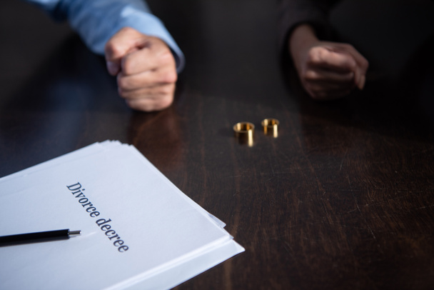 partial view of couple at table with divorce documents and rings - Photo, Image