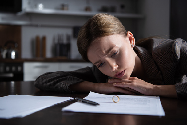 trieste jonge vrouw aan tafel met scheiding documenten - Foto, afbeelding