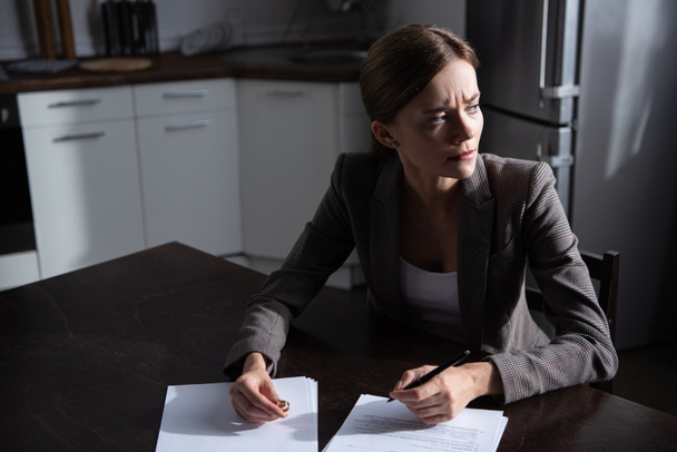 trieste jonge vrouw aan tafel met scheiding documenten - Foto, afbeelding