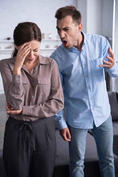 aggressive man in shirt screaming at scared wife at home - Foto, immagini