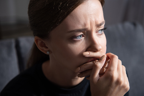 upset young woman covering mouth with hand and looking away  - Photo, Image