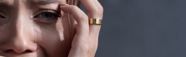 tiro panorâmico de mulher chorando em anel isolado em cinza
 - Foto, Imagem