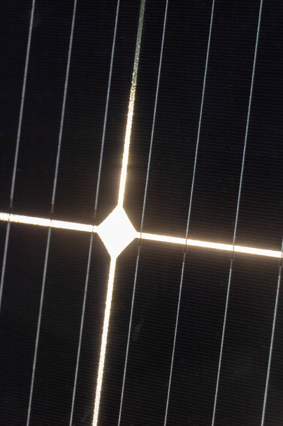 lähikuva auringonvaloa vastaanottavasta aurinkosähkökennosta, jonka heijastus muodostaa kristityn valovoiman ristin
 - Valokuva, kuva