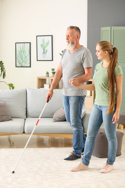 Woman helping blind mature man at home - Foto, Imagen