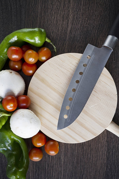 Un cuchillo profesional sobre una mesa de madera para cortar verduras y alimentos
 - Foto, imagen