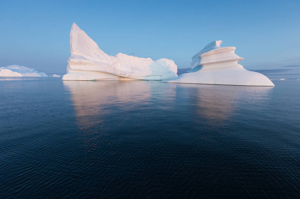 Valtavia, eri muotoisia jäävuoria Diskonlahdella, Länsi-Grönlannissa. Heidän lähteensä on Jakobshavnin jäätikkö. Tämä on seurausta ilmaston lämpenemisestä ja jään katastrofaalisesta sulamisesta.
  - Valokuva, kuva