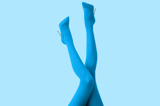 Legs of beautiful young woman in tights and high-heeled shoes on color background - Photo, Image
