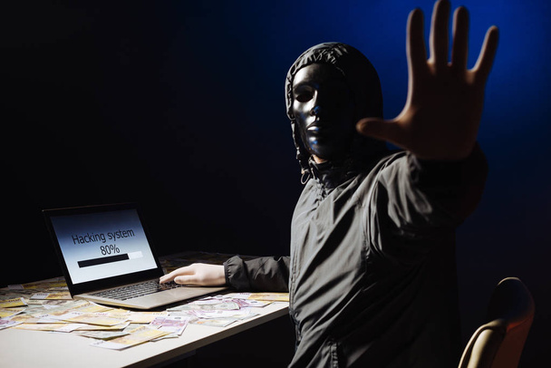 Ανώνυμος χάκερ προγραμματιστής χρησιμοποιεί ένα laptop να hack το σύστημα στο σκοτάδι. Δημιουργία και λοίμωξη από κακόβουλο ιό. Η έννοια του εγκλήματος στον κυβερνοχώρο και hacking βάσης δεδομένων - Φωτογραφία, εικόνα