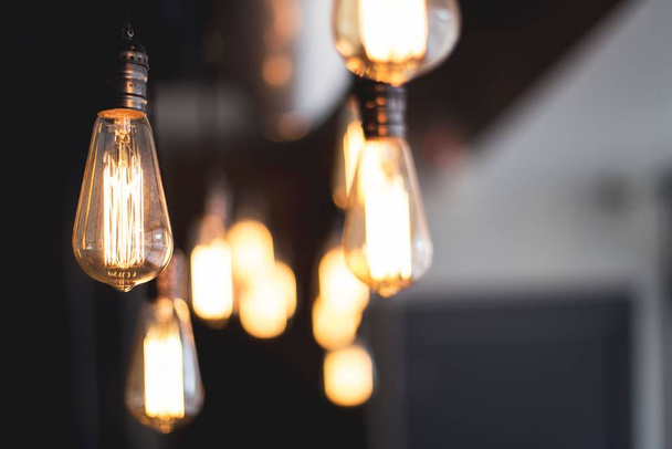 Wide selective closeup shot of illuminated light bulbs hanging from a ceiling - Fotografie, Obrázek