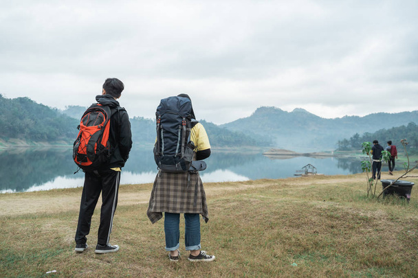 couple hikers with backpacks enjoying lake view - 写真・画像