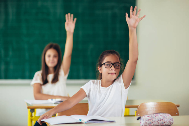 Los niños de la escuela levantaron las manos en clase
 - Foto, Imagen