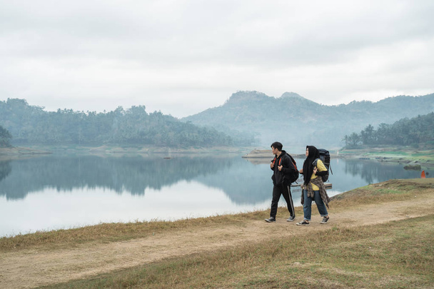 couple hikers with backpacks walking side the lake - 写真・画像