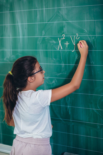 Happy schoolchild writing on blackboard - Φωτογραφία, εικόνα