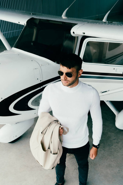 high angle view of man in sunglasses and casual attire near plane - Фото, изображение