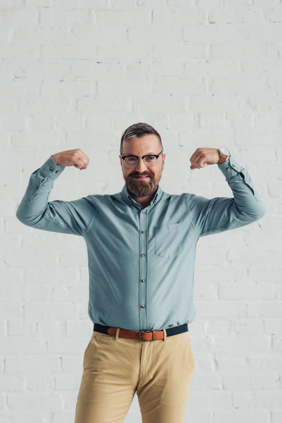 guapo y sonriente hombre de negocios en camisa mostrando gesto en la oficina
  - Foto, Imagen