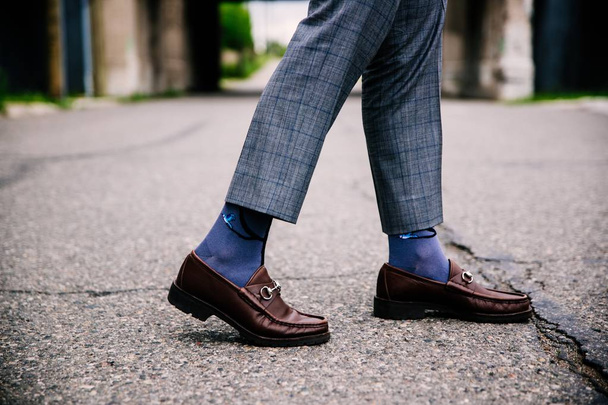 Selective closeup shot of a person wearing blue pants and brown shoes with blue socks - Fotoğraf, Görsel