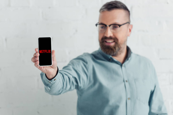 Київ, Україна-27 серпня 2019: селективний фокус гарного бізнесмена тримає смартфон з логотипом Netflix - Фото, зображення