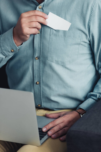 vue recadrée de l'homme d'affaires en chemise tenant carte blanche et ordinateur portable
  - Photo, image