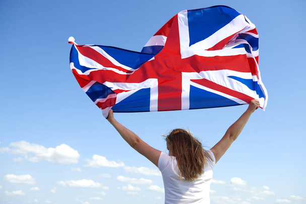 Visão traseira da jovem acenando com a bandeira britânica
  - Foto, Imagem