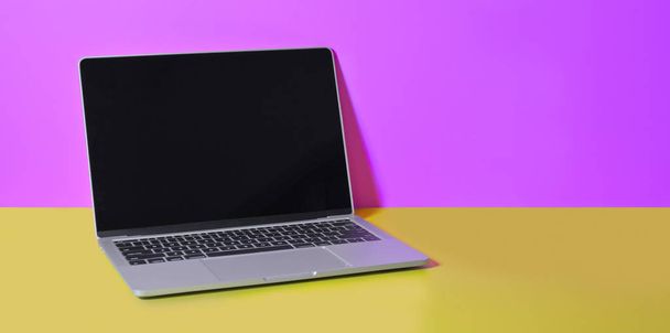 Computer portatile aperto su scrivania gialla e sfondo della parete rosa
  - Foto, immagini