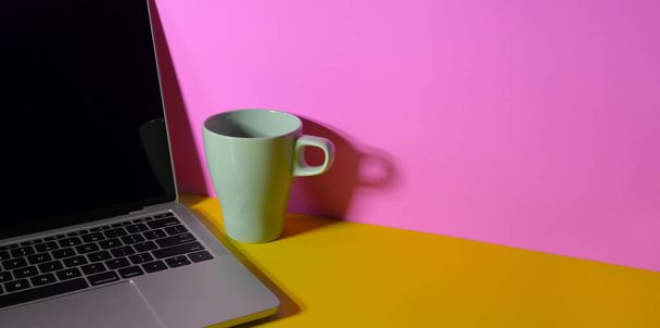 Lieu de travail coloré à la mode avec ordinateur portable, tasse à café et
  - Photo, image