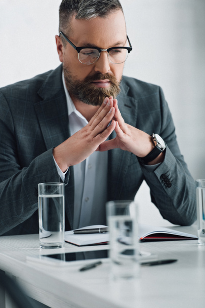 guapo hombre de negocios en ropa formal y gafas mirando hacia otro lado en la oficina
  - Foto, Imagen