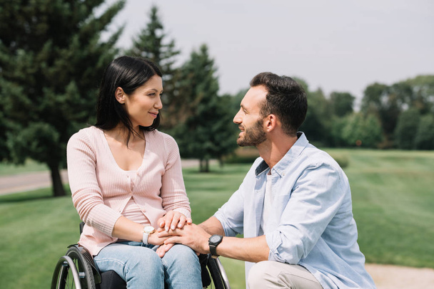 happy handsome man looking at smiling disabled girlfriend in park - Foto, Bild