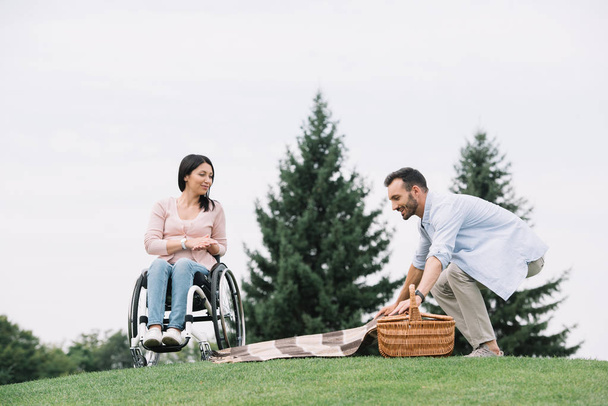 boldog ember készül helyet a piknik közelében fogyatékos barátnője a parkban - Fotó, kép