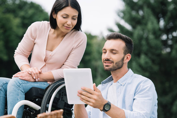 happy disabled woman and smiling boyfriend using digital tablet in park - Фото, зображення