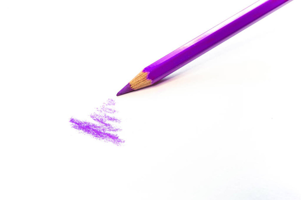 Ένα μωβ μολύβι αντλεί σε μια λευκή επιφάνεια απομονωμένη σε λευκό. Προμήθειες για καλλιτέχνες και σχολεία. - Φωτογραφία, εικόνα