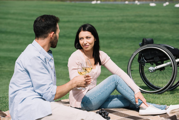 iloinen vammainen nainen clinking viinilasit poikaystävä istuessaan huopa puistossa
 - Valokuva, kuva