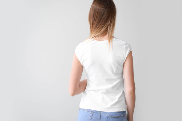 Woman in stylish t-shirt on light background, back view - Fotoğraf, Görsel