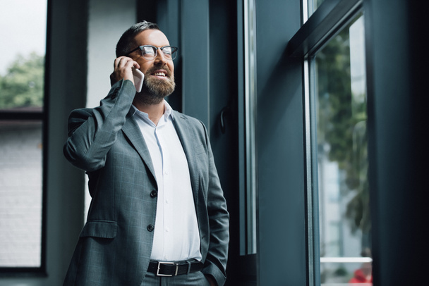 handsome businessman in formal wear and glasses talking on smartphone  - Фото, изображение