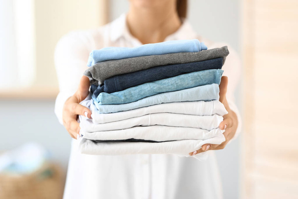 Mulher bonita com pilha de toalhas limpas em casa
 - Foto, Imagem