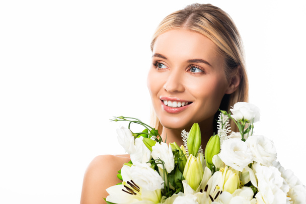 ξανθιά χαμογελαστή γυναίκα με τα λουλούδια κοιτάζοντας μακριά απομονωμένη σε λευκό - Φωτογραφία, εικόνα