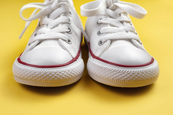 Photo of white sneakers over yellow background. - 写真・画像