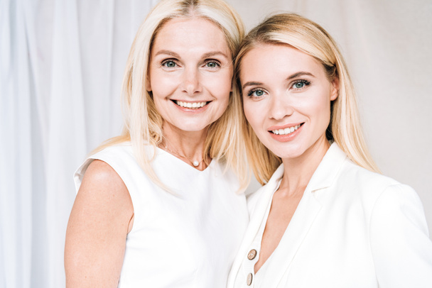 smiling blonde mother and daughter in total white outfits - Photo, Image