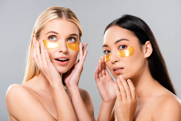 mooie Aziatische en Europese naakte meisjes met Eye patches op gezicht geïsoleerd op grijs - Foto, afbeelding