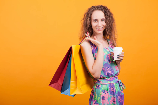 Uśmiechnięta kobieta trzyma swoje torby na zakupy i jej smaczną kawę - Zdjęcie, obraz