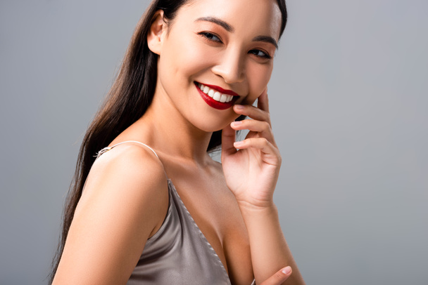 灰色に隔離された赤い唇を持つサティンドレスで幸せなアジアの女性 - 写真・画像