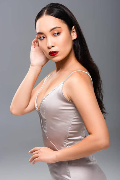 beautiful asian woman in satin dress with red lips isolated on grey - Zdjęcie, obraz