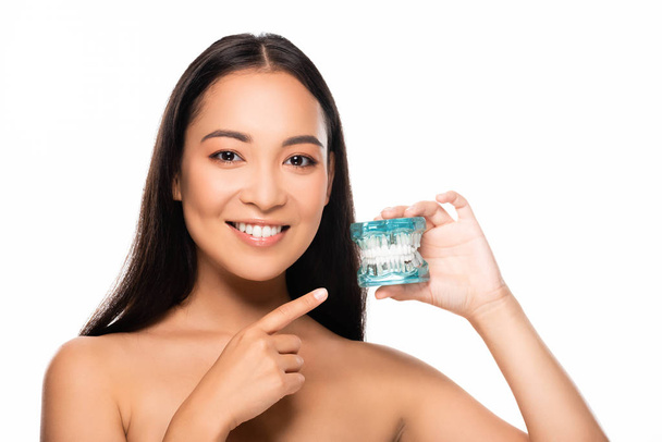 sonriente desnudo asiático mujer apuntando con dedo a la mandíbula modelo aislado en blanco
 - Foto, imagen